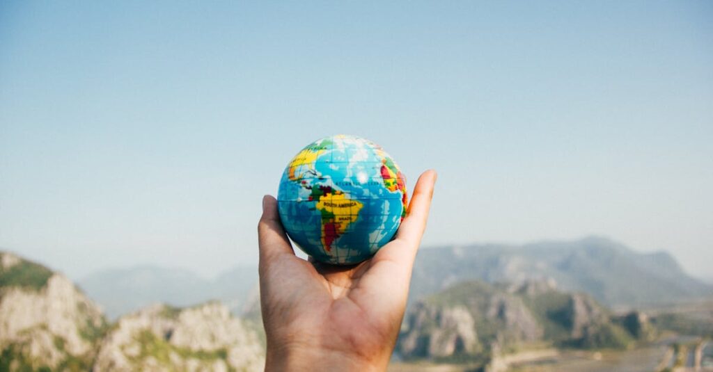 Person Holding World Globe Facing Mountain. Book flights and hotels